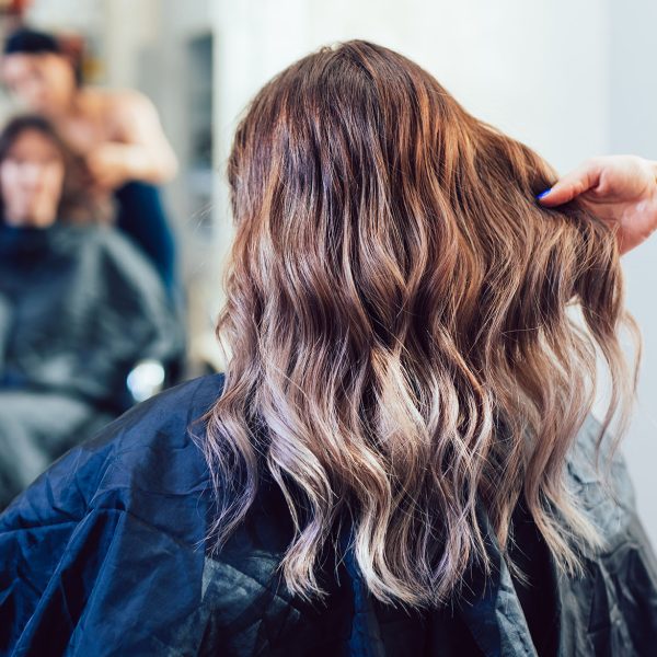 Beautiful hairstyle of young woman after dying hair and making highlights in hair salon.